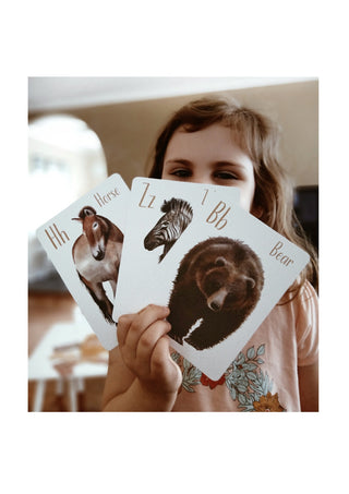 Little Girl holding 3 Modern Monty Animal Alphabet Flash Cards 
