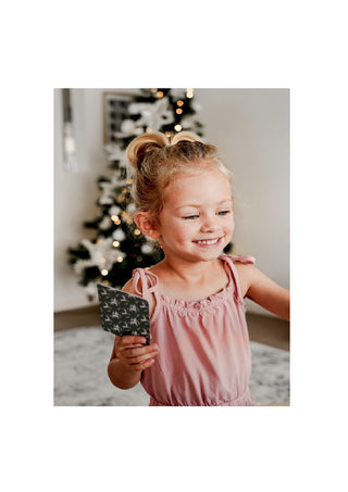 Little Girl in front of Christmas Tree holding Modern Monty's Christmas Snap & Go Fish 