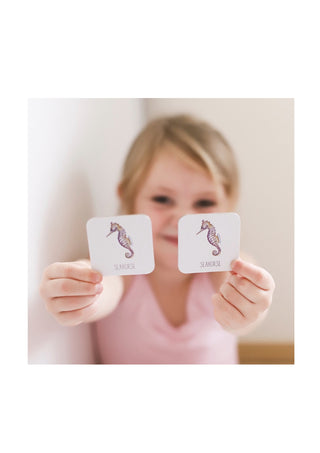 Little Girl holding up to matching cards from Modern Monty's Ocean Memory Card Game