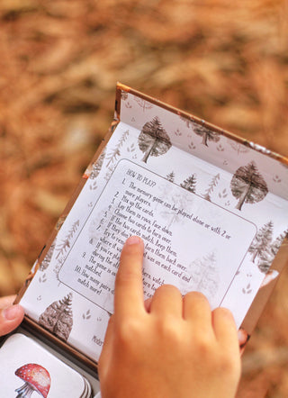 A child pointing to the How to Play instructions of a Modern Monty's Woodland Memory Card Game
